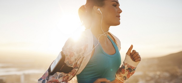 Close-up shot of fitness woman running outdoors. Caucasian female jogging in morning with bright sunlight.